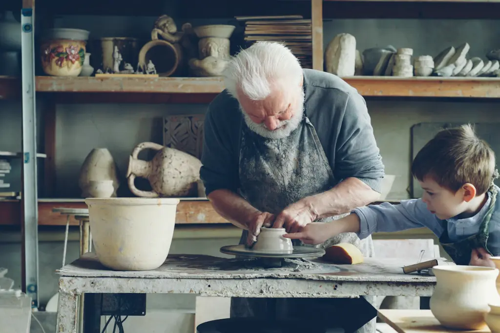 An older potter teaches a child how to mold clay.